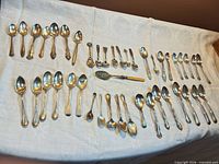 full lot of assorted spoons laid out on cloth