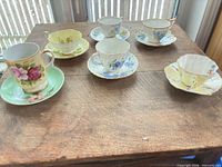 Six teacup and saucer sets arranged on table