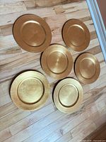 Six gold charger plates on floor
