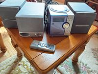 Front view of Centrios main unit between two speakers with remote in foreground