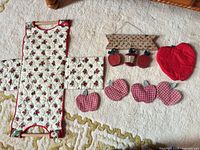 All items laid out: hanging towel holder, square pot holder, plaid apple coasters, red apple potholder, wooden sign