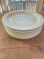 Stack of six off-white plates showing rim and profile
