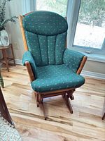 Front view of green upholstered oak glider rocking armchair