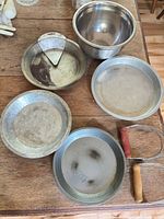 Overhead view of four pie pans, mixing bowl and both pastry blenders on tabletop