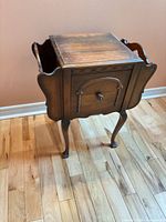 Front and side view of walnut sewing cabinet showing overall form and carved details