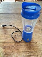 Full view of blue personal blender with blending cup and cord