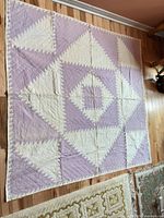 Entire quilt laid flat showing full lavender and cream pineapple pattern