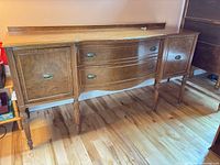 Full view of brown wood veneer sideboard showing drawers, cabinet doors and legs