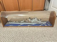 Full view of model ship inside acrylic dome on carpeted floor