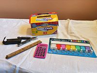 Group shot of all items: chalk box, multi-tool, ruler, calculator, key-tag rack