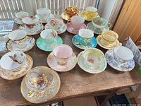 All 15 teacup and saucer sets arranged on table