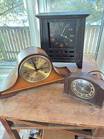 All three mantel clocks on table showing overall forms and relative sizes