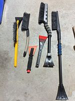 Six brushes and scrapers laid out on floor