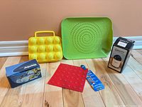 All five kitchen items grouped: boxed Danby egg cooker, boxed Graty tool, yellow egg holder, green draining mat, red trivet