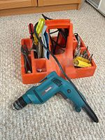 Makita drill, bits, screwdrivers, pliers and caddy overall view