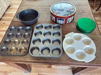 Group view: two muffin pans, cake pan, Rubbermaid cooker, holiday tin, green tins