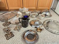 overview of all silver-plated trays, candlesticks, covered dishes, pitcher, gravy boat, and glass bowls