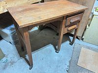 Full view of oak writing desk showing drawers and casters