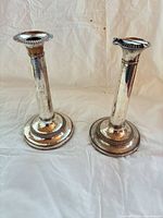 Both candlesticks upright on backdrop showing overall form and tarnish