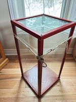 Full view of red-stained wood and glass display case on floor