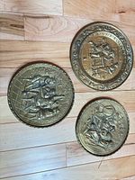 All three round embossed metal plaques displayed