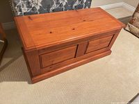 Closed solid wood chest showing paneled front and honey pine finish