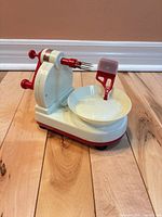 Front view of plastic apple peeler showing crank handle, prongs and bowl