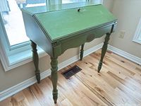 Full view of closed green drop-front desk on turned legs