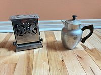 Chrome manual toaster and aluminum pitcher on floor
