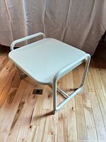 Full view of white metal side table on hardwood floor