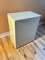Closed white painted plywood blanket chest on floor