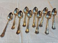 Twelve ornate silver-plated teaspoons fronts displayed