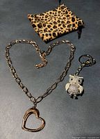 Necklace, owl keychain and pouch laid out together