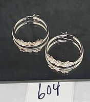 Pair of sterling silver floral hoop earrings on black surface