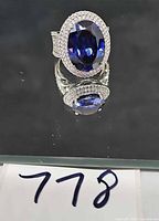 Front view of sterling silver ring showing oval blue stone and halo of clear stones