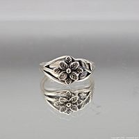 Full view of sterling silver floral ring on reflective surface