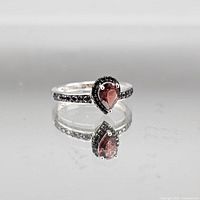 Full view of ring on reflective surface showing design and stones