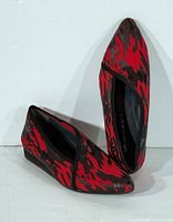 Side view of both shoes showing red/black pattern and low wedge