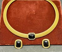 Choker necklace and earrings laid out on red display pad