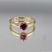 Full view of ring showing red gemstone and yellow gold tone band