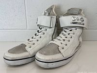 Three-quarter view of both sneakers showing leather, mesh, and logo strap