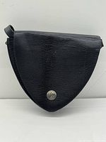 Front view of black triangular leather satchel with logo medallion