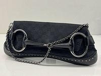 Front view of black GG canvas clutch showing silver horsebit and chain strap