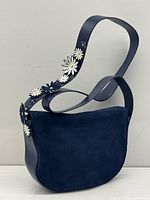 Front view showing navy leather body, suede panel, floral strap detail