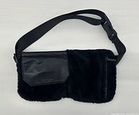 Front view showing fleece body, leather flap pocket, zip pocket, and strap