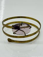 Top view of brass spiral bracelet with purple glass cabochon