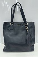 front view of Michael Kors black leather tote showing gold hardware and tassel