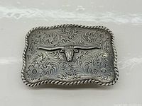 Front view showing engraved floral design, longhorn motif, rope edge