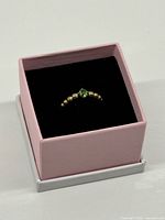 Ring in pink box showing beaded design and green stone