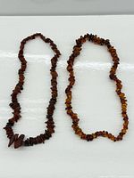 Both amber chip-bead necklaces laid flat